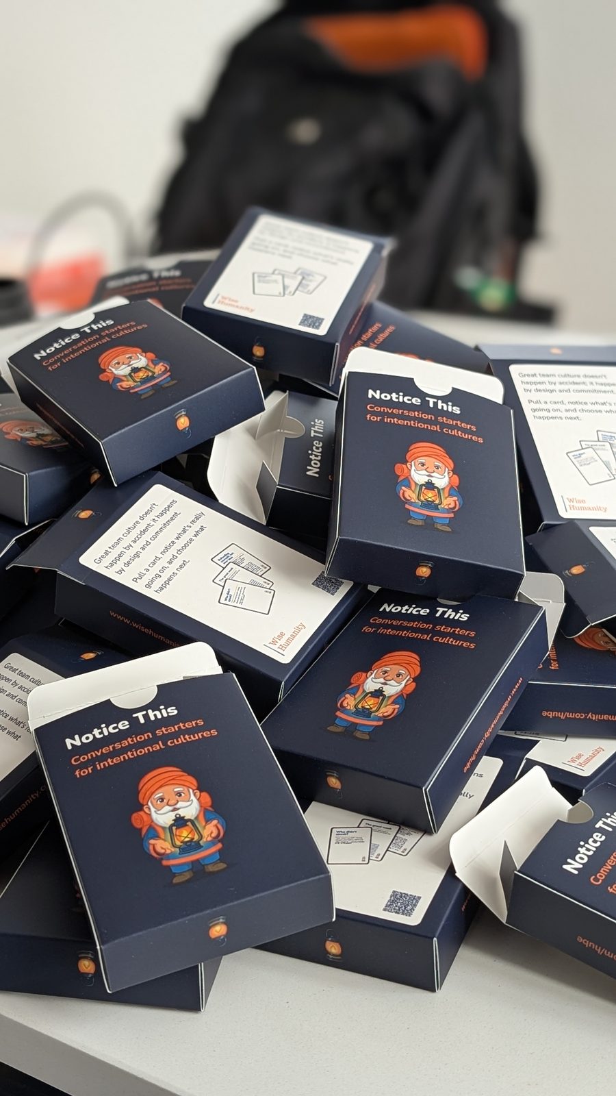 Boxed decks of Notice this cards stacked before the summit