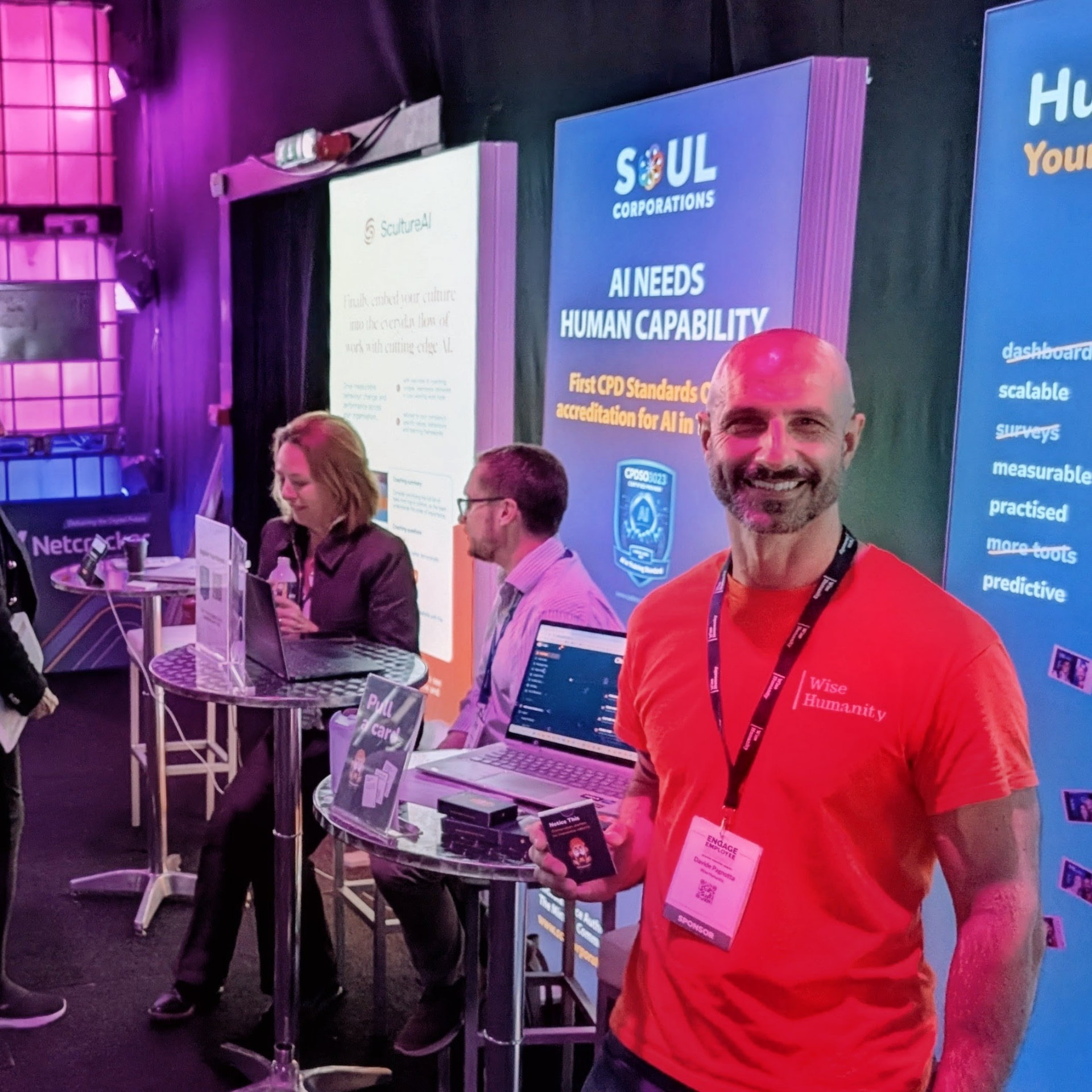 Davide holding a Notice this card on the Hu.Be stand at the Engage Employee Summit in London