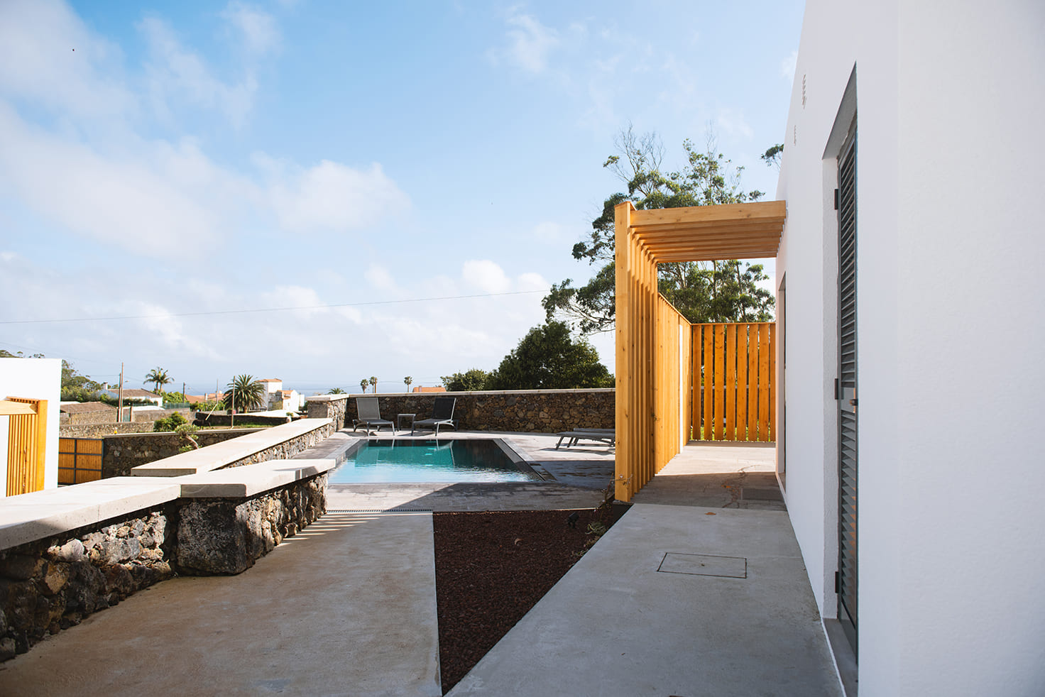 The swimming pool at Vilas do Olival beside white villas and a wooden pergola