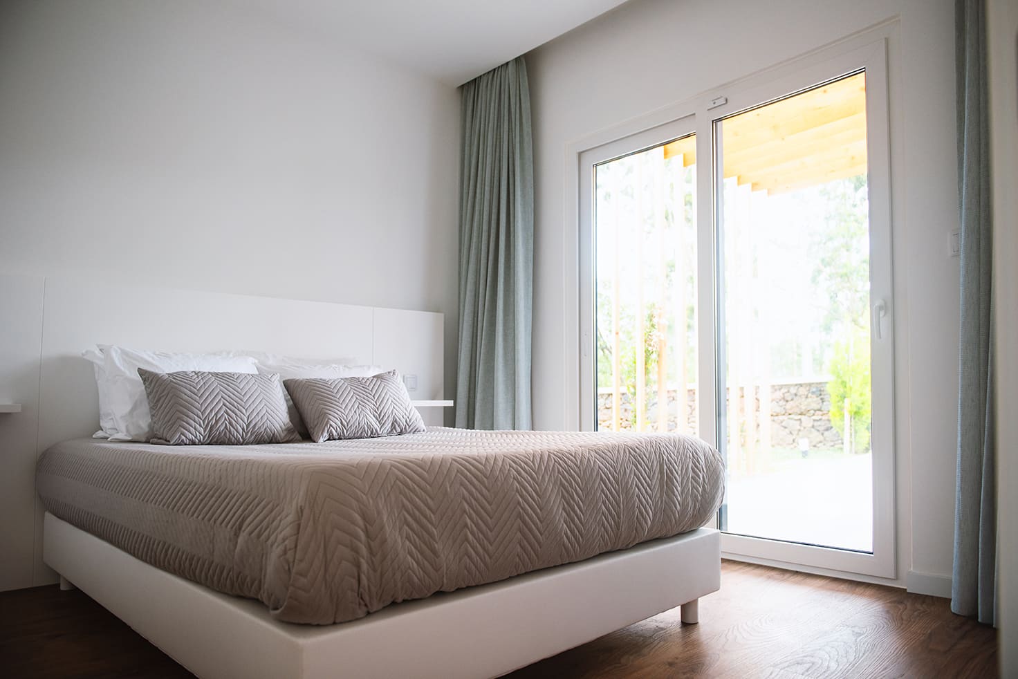 A bright bedroom at Vilas do Olival with glass doors onto the garden